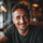 Homme souriant dans un café chaleureux.
