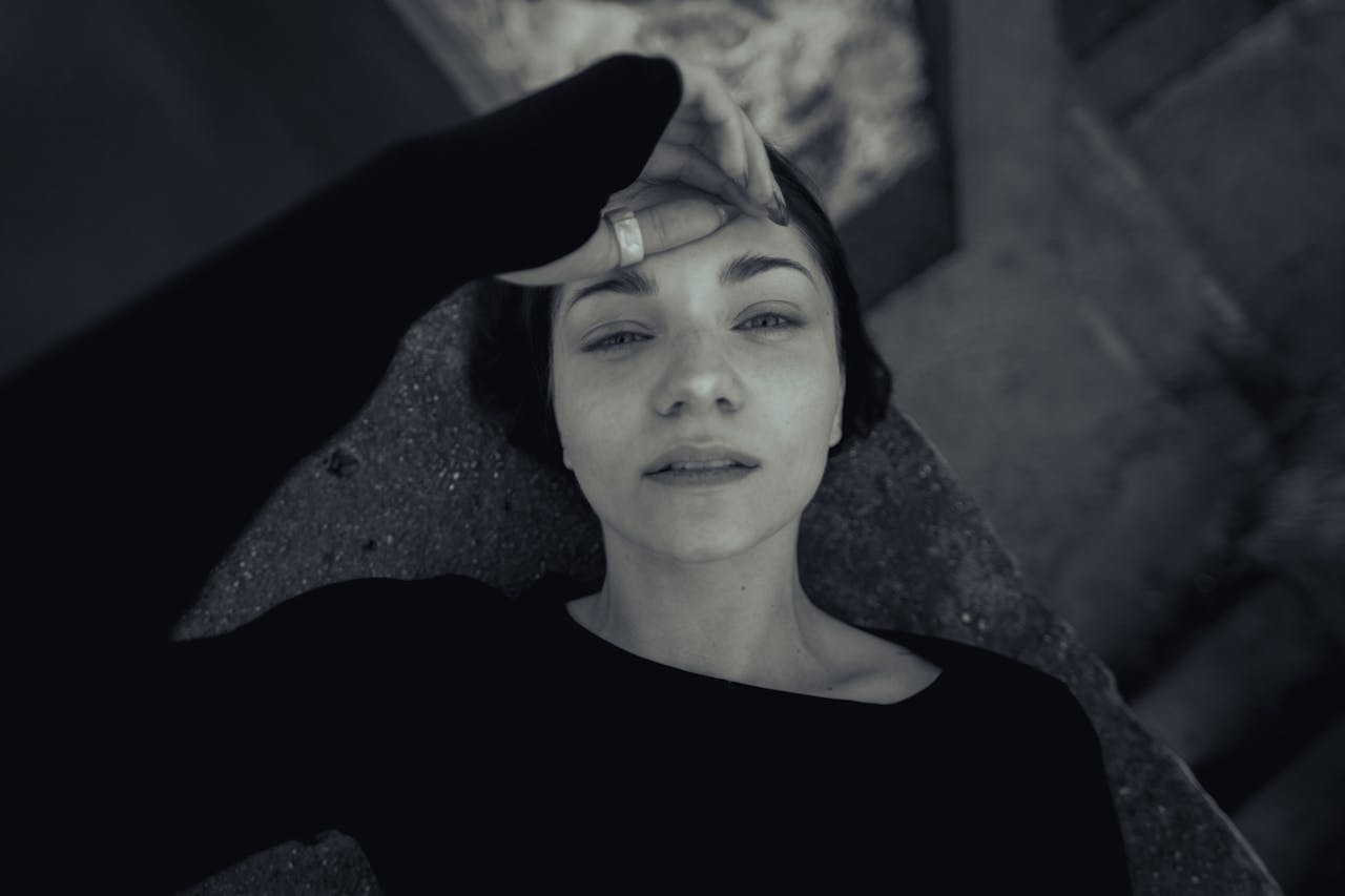 Black and white portrait of a relaxed woman lying outdoors, conveying emotion and introspection.